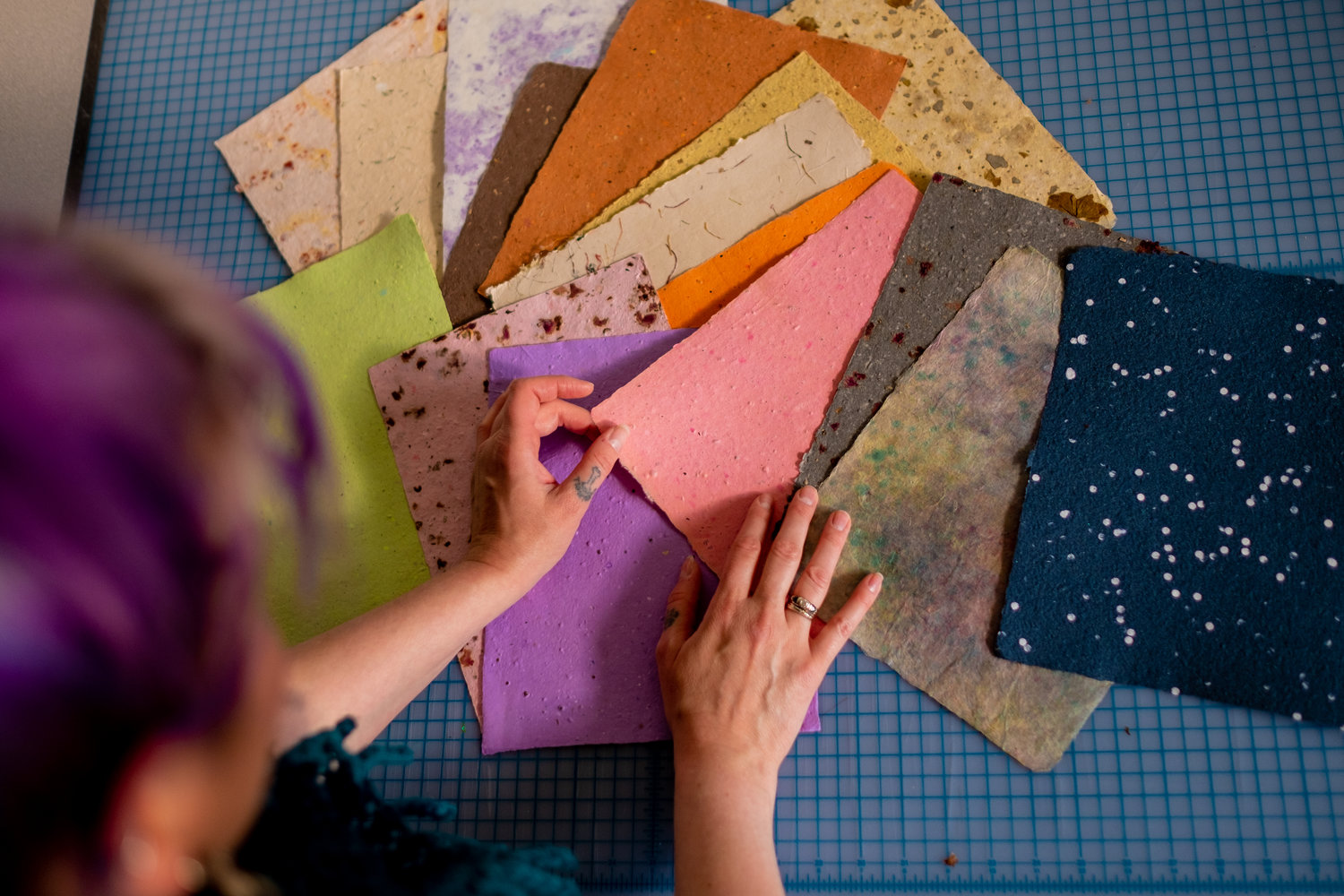 Papers of different colors yellow, green, purple, pink spread out on a table