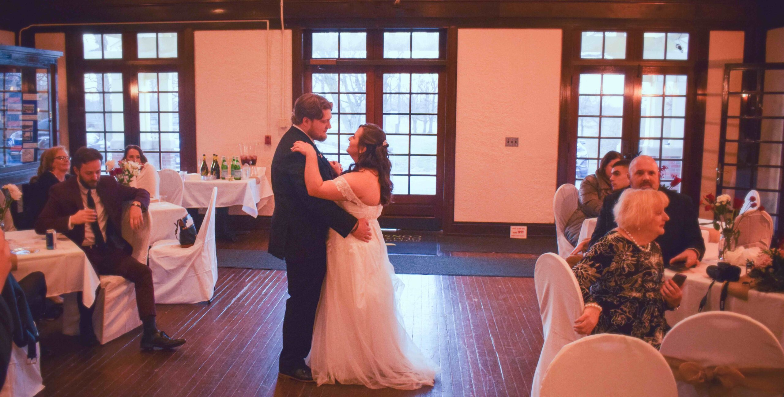 Bride and groom dancing in the Parkside Lodge, with guests seated